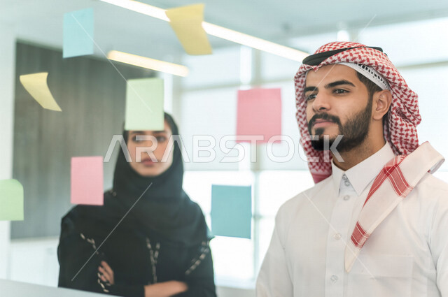 موظفان عربيان خليجيان سعوديان ينظران الى الملاحظات المعلقة ،المشاركة بتحديد الاهداف ، انجاز مهام العمل ، تحقيق اهداف الشركة ، تطوير العمل