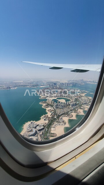 شركات وخطوط الطيران القطري، توفير الخدمات المتطورة لسهولة التنقل بين البلدان، مفهوم السياحة والسفر، صورة جوية لمعالم قطر من نافذة طائرة تحلق فوق البحر في السماء، وسائل النقل والمواصلات الجوية