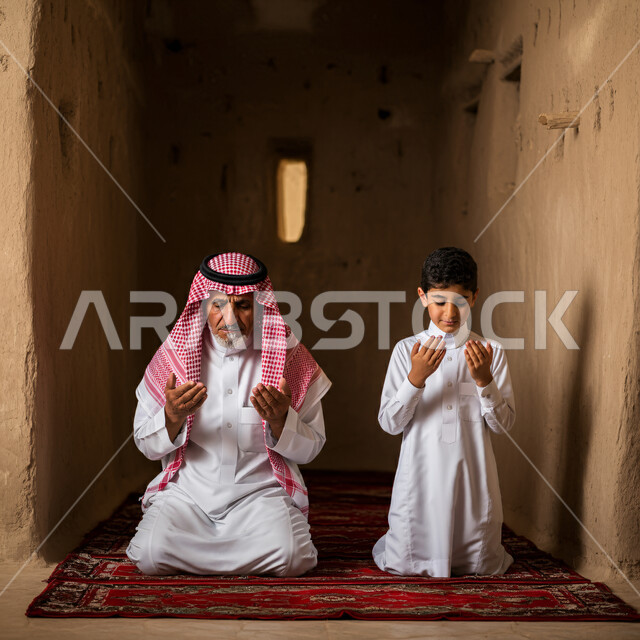 الإكثار من الطاعات وذكر الله تعالى، رجل كبير بالسن عربي سعودي خليجي يجلس على السجادة يؤدي فرض الصلاة بجانب ابنه الصبي يرفعان أيديهما يقومان بالدعاء، التقرب إلى رب العالمين في شهر رمضان، الاجتهاد في العبادة وأداء الفرائض الدينية، أجواء عائلية رمضانية روحانية