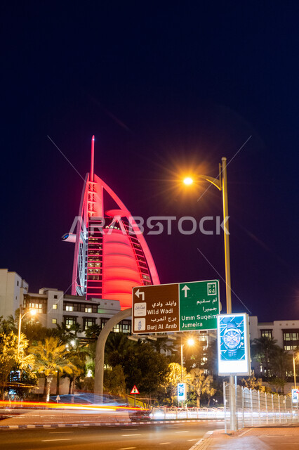 Urban growth and development of hotels and resorts in the United Arab Emirates, modern architectural art of towers and skyscrapers, Burj Al Arab illuminated at night in Dubai, attracting and attracting tourists from all over the world, traffic on public streets