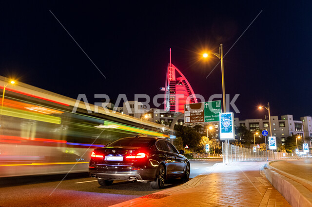 النمو والتطور العمراني للفنادق والمنتجعات في الإمارات العربية المتحدة، الفن الهندسي المعماري على الطراز الحديث للأبراج وناطحات السحاب، برج العرب المضاء ليلا في مدينة دبي، جذب واستقطاب السياح من انحاء العالم، حركة مرور السيارات في الشوارع العامة