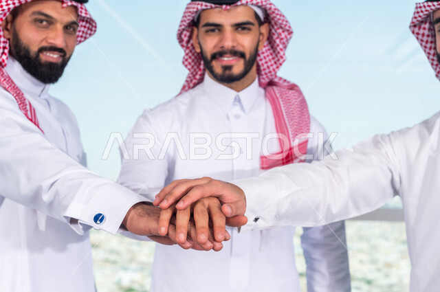 صورة لفريق عمل خليجي سعودي يضعون ايديهم فوق بعضها، فريق عمل ناجح، الوحدة والعمل الجماعي ، انجاز مهام العمل ، تحقيق اهداف الشركة ، تطوير العمل