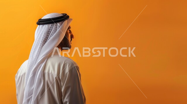 الاهتمام بالمظهر الخارجي, مفهوم الأناقة و الرجولة, الوقوف باستقامة و اعتدال, بورتريه مقرب من الخلف لرجل عربي خليجي سعودي يرتدي الثوب التقليدي و الغترة ينظر إلى شيء ما, خلفية صفراء