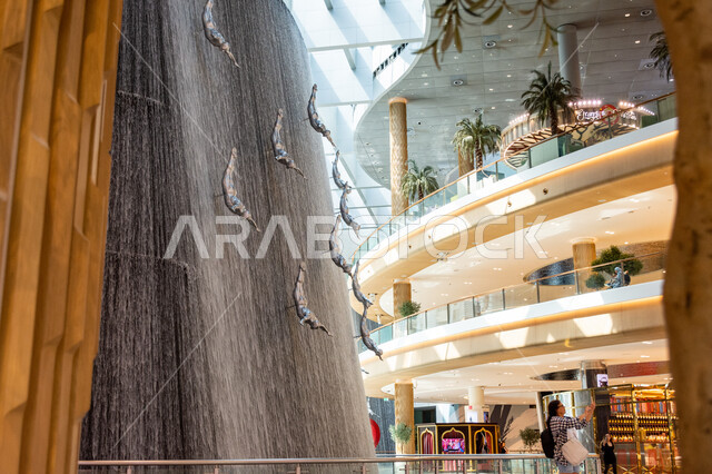 الفن الهندسي والتصاميم الداخلية للمولات، أماكن الأنشطة العائلية الترفيهية، جذب واستقطاب السائحين من أنحاء العالم، السياحة في الإمارات العربية المتحدة، تماثيل فنية لغواصي اللؤلؤ المعلقة وسط الشلال، صورة لمجموعة من تماثيل الغطاس داخل دبي مول بإمارة دبي