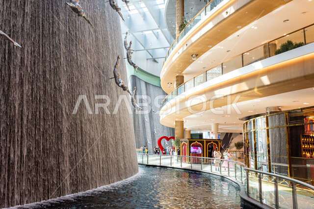 الفن الهندسي والتصاميم الداخلية للمولات، أماكن الأنشطة العائلية الترفيهية، جذب واستقطاب السائحين من أنحاء العالم، السياحة في الإمارات العربية المتحدة، تماثيل فنية لغواصي اللؤلؤ المعلقة وسط الشلال، صورة لمجموعة من تماثيل الغطاس داخل دبي مول بإمارة دبي