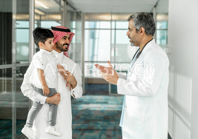 أب سعودي خليجي مع ابنه الصغير في زيارة الى دكتور الأطفال داخل المستشفى ، موعد مع الطبيب للمراجعة وتلقي الاستشارات والتعليمات الطبية ، مستشفى خاص بالأطفال ، مفهوم الطب والرعاية الصحية ، الرعاية الطبية للأطفال