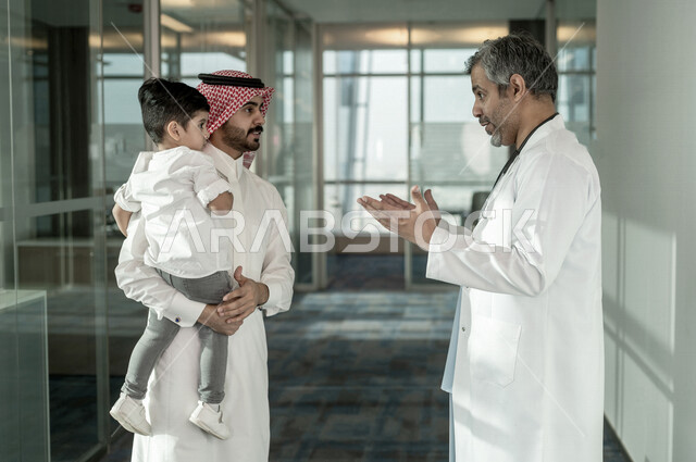 أب سعودي خليجي مع ابنه الصغير في زيارة الى دكتور الأطفال داخل المستشفى ، موعد مع الطبيب للمراجعة وتلقي الاستشارات والتعليمات الطبية ، مستشفى خاص بالأطفال ، مفهوم الطب والرعاية الصحية ، الرعاية الطبية للأطفال