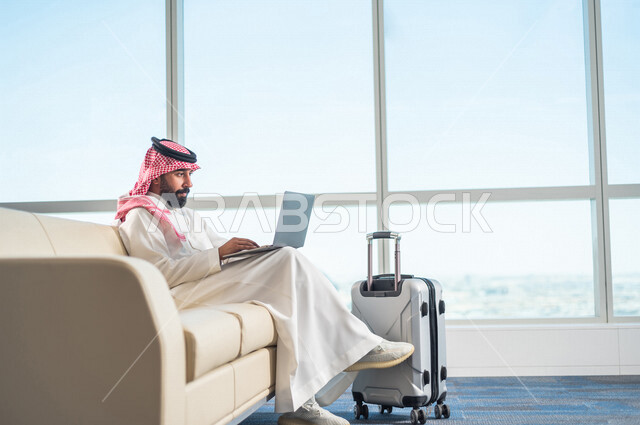 A Saudi Arabian Gulf businessman, getting work done through a laptop, getting ready to travel on a business trip, waiting hall at the airport, tourism and travel