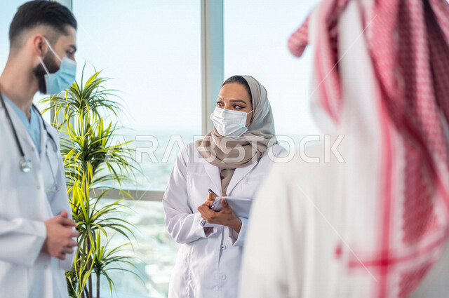A picture of a Saudi Arabian Gulf medical team, discussing work tasks, recording notes, unity and teamwork, adhering to preventive measures against the Corona virus, developing work