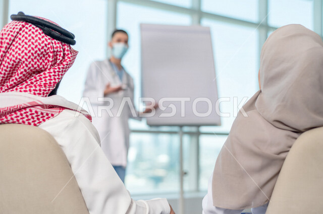 فريق طبي عربي خليجي سعودي، تبادل الاستشارات الطبية، العمل الجماعي للأطباء، ارتداء الكمامة، تقديم دورة، الشرح على لوح ابيض، مفهوم الطب والرعاية الصحية