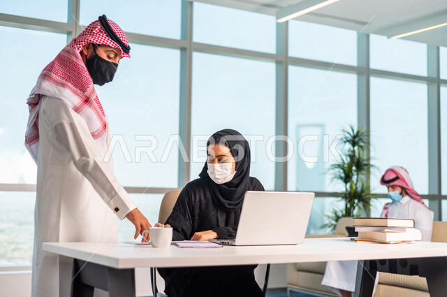 مناقشة عمل بين  رجل عربي سعودي خليجي مع زميلته في شركه , توزيع مهام واعمال الشركه, بيئة العمل السعودي الخليجي,  ارشاد وتوجيه , الالتزام بالاحترازات الوقائيه في بيئة العمل السعودي
