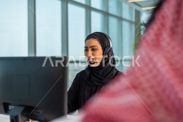 موظفان عربيان سعوديان خليجيان يعملان في خدمة العملاء , اجراء اتصال فيديو من خلال الحاسوب , عقد اجتماع عمل عبر الانترنت , العمل عن بعد , متابعة وتطوير العمل