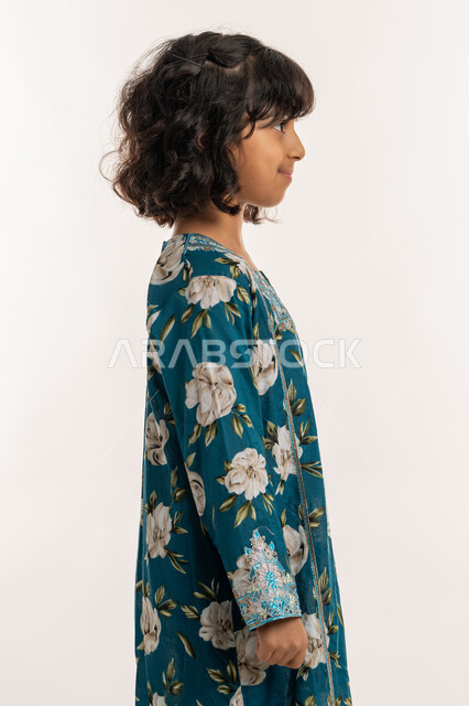 الاهتمام بالمظهر الخارجي، ايماءات الثقة بالنفس، حب التزين وارتداء الملابس الجديدة، مفهوم الاناقة والنعومة، بورتريه من الجانب لفتاة عربية خليجية اماراتية ترتدي فستان العيد، بنت سعودية انيقة تقف باستقامة، خلفية بيضاء