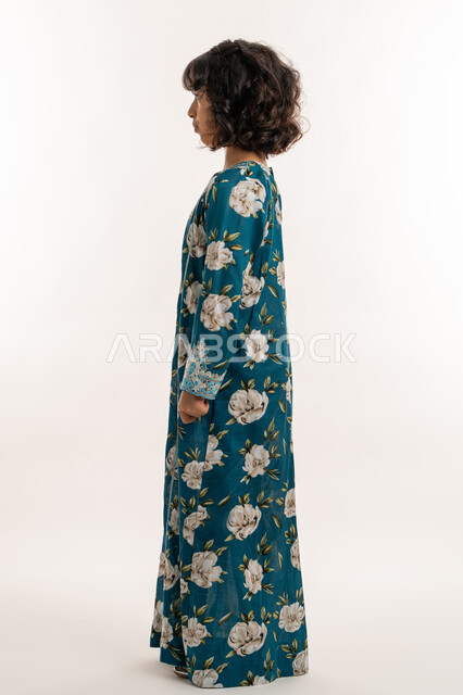 Self-confidence gestures, love of adornment and wearing new clothes, concept of elegance and softness, interest in external appearance, side portrait of an Arab Gulf Emirati girl wearing an Eid dress, elegant Saudi girl standing straight, full body photo, white background