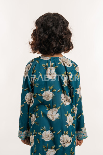 الاهتمام بالمظهر الخارجي، حب التزين وارتداء الملابس الجديدة، مفهوم الاناقة والنعومة، بورتريه من الخلف لفتاة عربية خليجية اماراتية ترتدي فستان العيد، بنت سعودية انيقة تقف باستقامة، خلفية بيضاء