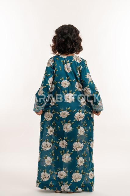 Love of adornment and wearing new clothes, the concept of elegance and softness, interest in external appearance, portrait from the back of an Arab Gulf Emirati girl wearing an Eid dress, elegantly holding the hem of her dress, an elegant Saudi girl standing straight, a full body image, white background