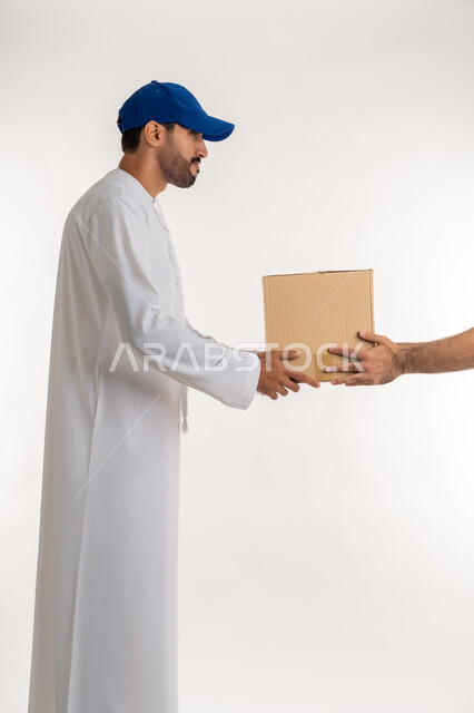 Customer order delivery process, online shopping and ordering, high quality shipping and delivery services, side portrait of a young Arab Gulf Emirati man wearing a kandura and a blue cap delivering goods, white background