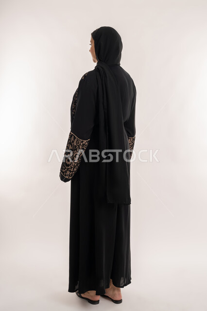 الاهتمام بالمظهر الخارجي, بورتريه من الجانب لامرأة عربية خليجية اماراتية محجبة ترتدي العباءة السوداء تقف باستقامة واستعداد، صورة الجسم باالطول الكامل, خلفية بيضاء