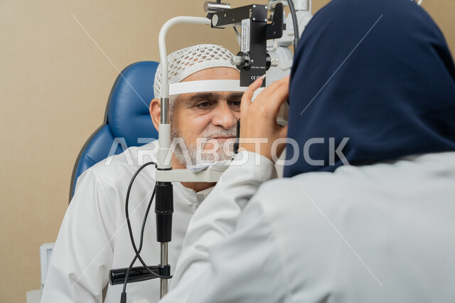 استخدام الأجهزة الحديثة المتطورة، تشخيص وتحديد المشاكل البصرية، صورة مقربة لطبيبة عربية خليجية اماراتية تقوم بفحص عيني رجل مسن اماراتي عربي خليجي بجهاز المنظار العيني، تقييم مدى الرؤية والكشف عن الامراض العينية، مفهوم الخدمات والرعاية الصحية في المشافي والمراكز الطبية