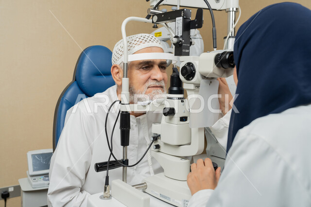 استخدام الأجهزة الحديثة المتطورة، تشخيص وتحديد المشاكل البصرية، صورة مقربة لطبيبة عربية خليجية اماراتية تقوم بفحص عيني رجل مسن اماراتي عربي خليجي بجهاز المنظار العيني، تقييم مدى الرؤية والكشف عن الامراض العينية، مفهوم الخدمات والرعاية الصحية في المشافي والمراكز الطبية