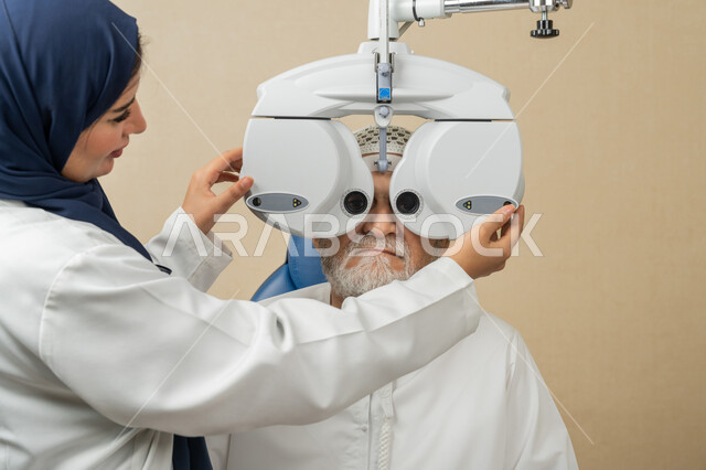 استخدام الأجهزة الحديثة المتطورة، تشخيص وتحديد المشاكل البصرية، صورة مقربة من الجانب لطبيبة عربية خليجية اماراتية تقوم بفحص عيني رجل مسن اماراتي عربي خليجي بجهاز المنظار العيني، تقييم مدى الرؤية والكشف عن الامراض العينية، مفهوم الخدمات والرعاية الصحية في المشافي والمراكز الطبية