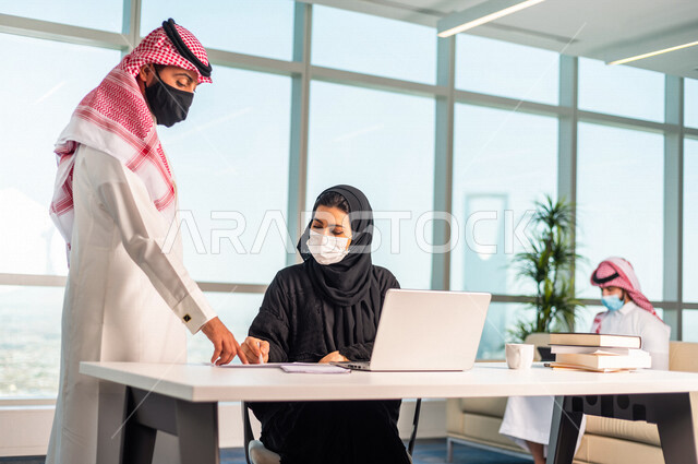 مناقشة عمل بين  رجل عربي سعودي خليجي مع زميلته في شركه  في المملكه العربيه السعوديه, تسليم مهام واعمال من موظف سعودي خليجي لموظفه سعوديه خليجيه, بيئة العمل السعودي الخليجي, الالتزام بالاحترازات الوقائيه في بيئة العمل السعودي