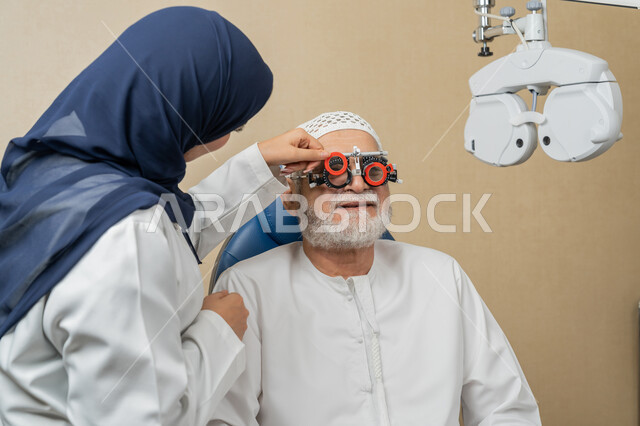 استخدام الأجهزة الحديثة المتطورة، تشخيص وتحديد المشاكل البصرية، صورة مقربة من الجانب لطبيبة عربية خليجية اماراتية تقوم بفحص عيني رجل مسن اماراتي عربي خليجي بجهاز المنظار العيني، تقييم مدى الرؤية والكشف عن الامراض العينية، مفهوم الخدمات والرعاية الصحية في المشافي والمراكز الطبية