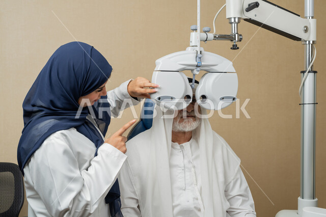 استخدام الأجهزة الحديثة المتطورة، تشخيص وتحديد المشاكل البصرية، صورة مقربة لطبيبة عربية خليجية اماراتية تقوم بفحص عيني رجل مسن اماراتي عربي خليجي بجهاز المنظار العيني، تقييم مدى الرؤية والكشف عن الامراض العينية، مفهوم الخدمات والرعاية الصحية في المشافي والمراكز الطبية