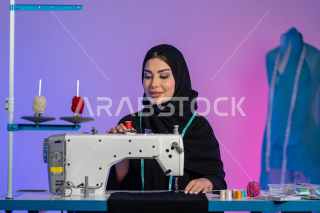 Arts, crafts and crafts, sewing art and fashion design, creating modern contemporary models, tailoring elegant women's clothing, close-up portrait of an Arab Gulf Emirati fashion designer wearing an abaya working on a machine, a Saudi woman sitting with gestures of confidence and integration, colorful background