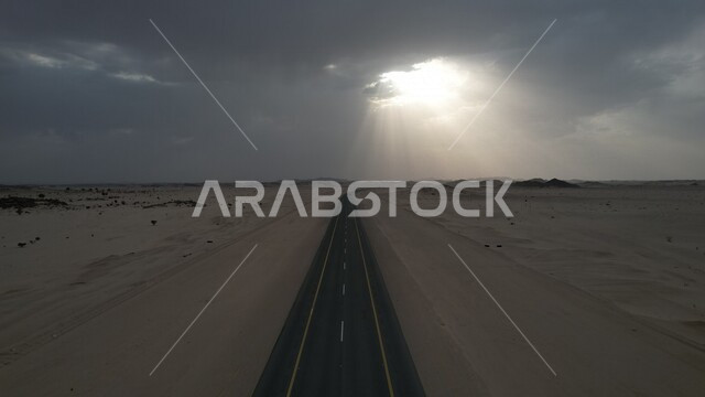 صورة لطريق صحراوي في المملكة العربية السعودية ، سماء ملبدة بالغيوم ، طريق سريع ، طريق اسفلتي نموذجي ، الطبيعة الصحراوية  في السعودية
