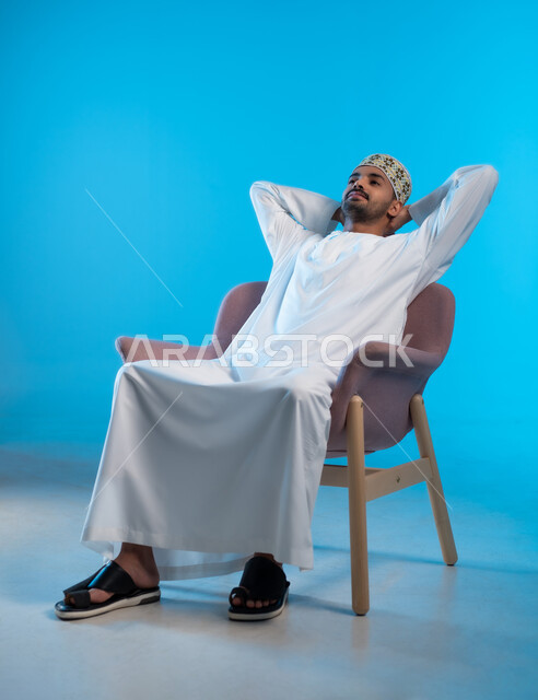 تعابير التأمل والتفكير، الحاجة إلى النوم والشعور بالتعب و الخمول, بورتريه لرجل عربي خليجي عماني يرتدي الكمة والدشداشة يجلس على كرسي مريح يضع يديه خلف راسه بإيماءات الراحة والإسترخاء, خلفية بيضاء