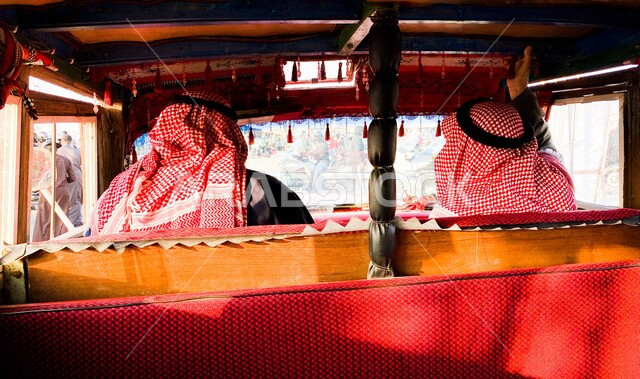 صورة مقربة من زاوية الخلف لشابان عربيان سعوديان خليجيان في داخل عربة ذات طراز قديم ، عربة عتيقة ، السياحة في السعودية 