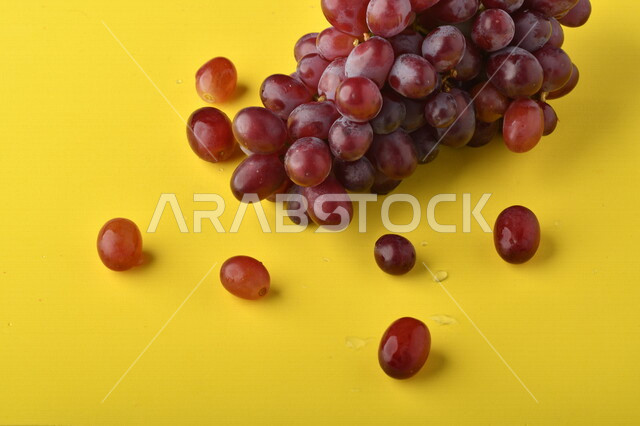 صورة لفاكهة العنب الأرجواني اللذيذ على خلفية صفراء ، فاكهة العنب الصحية اللذيذة تظهر على شكل عناقيد ، فاكهة صيفية