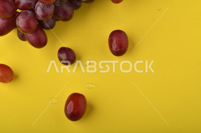 صورة لفاكهة العنب الأرجواني اللذيذ على خلفية صفراء ، فاكهة العنب الصحية اللذيذة تظهر على شكل عناقيد ، فاكهة صيفية
