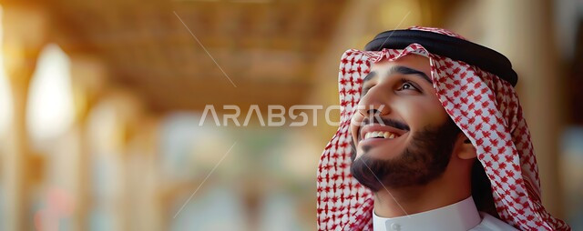 الرجولة والأناقة والاهتمام بالمظهر الخارجي، صورة مقربة لرجل سعودي عربي خليجي مبتسم يرتدي الثوب التقليدي والشماغ ينظر إلى الأعلى بتعابير البشاشة، التركيز على شيء  بايماءات السرور والسعادة، مفهوم التأمل والتخطيط للمستقبل