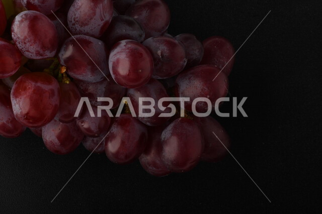 Image of delicious purple grapes on black background, delicious healthy grapes appear in clusters, summer fruit
