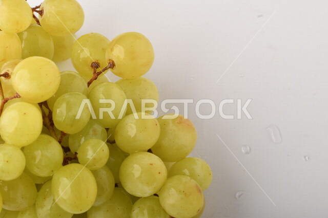 فاكهة العنب الأخضر اللذيذ على خلفية بيضاء ، صورة مقربة لفاكهة العنب الصحية اللذيذة تظهر على شكل عناقيد ، فاكهة صيفية