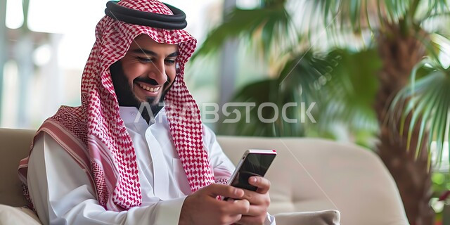 Chatting with friends via mobile programs and applications, browsing social networking sites, a Saudi Arabian Gulf man wearing a traditional shemagh and thobe holding a mobile phone in his hand, integrating modern technologies and technology into practical life, gestures of happiness and pleasure when hearing good news