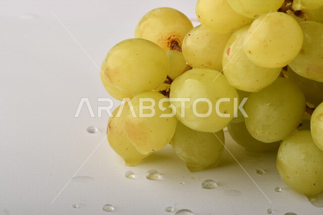 فاكهة العنب الأخضر اللذيذ على خلفية بيضاء ، صورة مقربة لفاكهة العنب الصحية اللذيذة تظهر على شكل عناقيد ، فاكهة صيفية