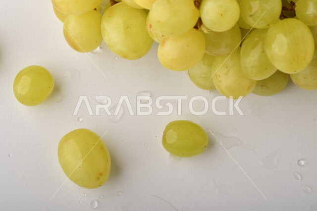فاكهة العنب الأخضر اللذيذ على خلفية بيضاء ، صورة مقربة لفاكهة العنب الصحية اللذيذة تظهر على شكل عناقيد ، فاكهة صيفية