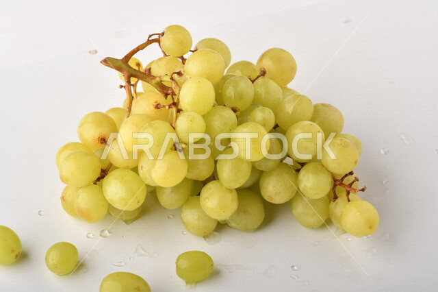 فاكهة العنب الأخضر اللذيذ على خلفية بيضاء ، صورة مقربة لفاكهة العنب الصحية اللذيذة تظهر على شكل عناقيد ، فاكهة صيفية
