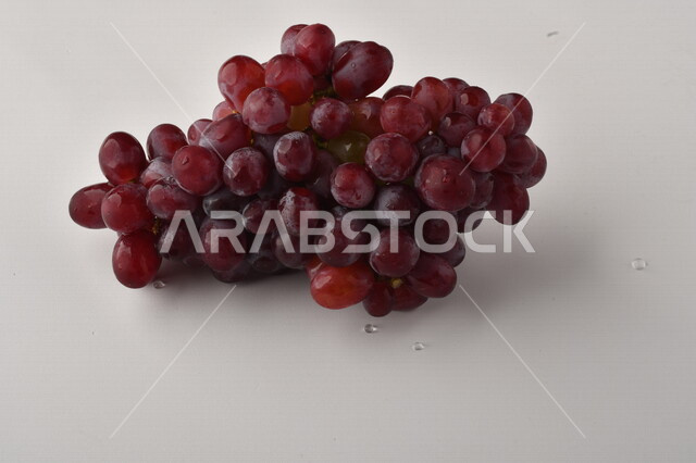 فاكهة العنب الأرجواني اللذيذ مصورة على خلفية بيضاء ، فاكهة العنب الصحية اللذيذة تظهر على شكل عناقيد ، فاكهة صيفية