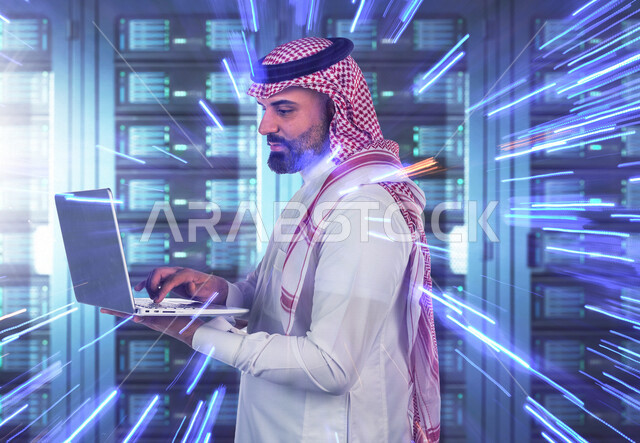 موظف عربي سعودي خليجي يعمل في مركز البيانات يقوم باستخدام جهاز تقني لادارة الخوادم, مجموعه من خوادم الانترنت والسيرفرات , حظيرة الخوادم, تقنيه وتكنولوجيا