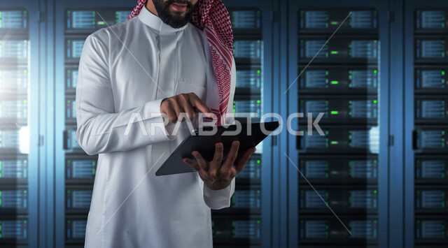موظف عربي سعودي خليجي يعمل في مركز البيانات يقوم باستخدام جهاز تقني لادارة الخوادم, مجموعه من خوادم الانترنت والسيرفرات , حظيرة الخوادم, تقنيه وتكنولوجيا