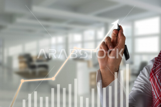 A close-up of the hand of a Saudi Arabian Gulf man, studying the financial market and financial feasibility, analyzing and drawing data with hologram technology, planning and analyzing data and information