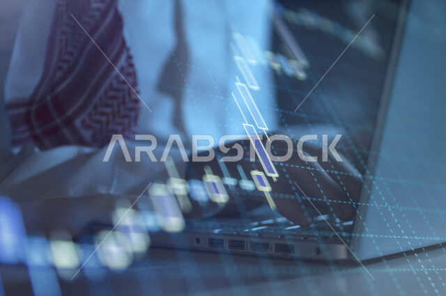 صورة مقربة ليد رجل عربي خليجي سعودي في مقر عمله بالشركة، يتابع البورصة من خلال استخدام الابتوب، رسومات بيانية، صعود ونزول البورصة المالية، الاستثمار المالي والاقتصادي، أعمال الكترونية تجارية