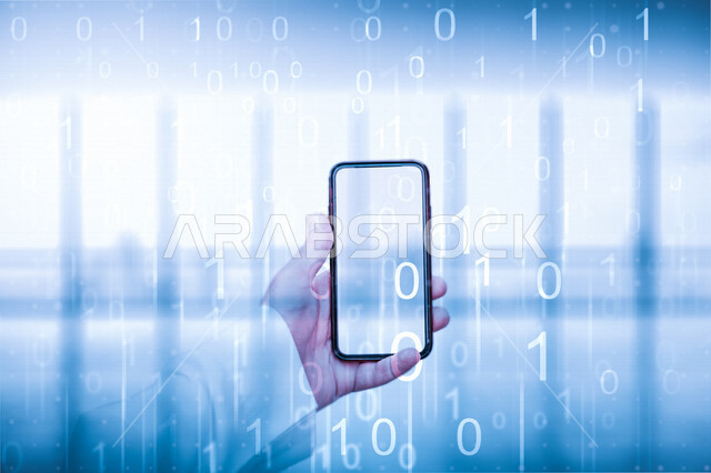 صورة مقربة ليد رجل عربي سعودي خليجي يحمل بيده هاتفه الذكي، جهاز تقني ذكي، اكواد وخوارزميات رقمية امام الهاتف المحمول
