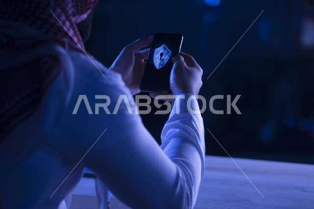 A Saudi Arabian Gulf man holding a mobile phone containing the logo of the smart electronic lock, the smart lock program, cyber security, risk management and information security.