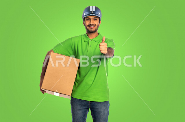 Chroma for a young Saudi Arabian Gulf man with a green background working to deliver orders, delivery of order boxes to customers to the door of the house, a reliable shipping and delivery process