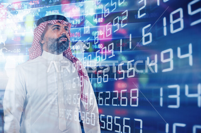 صورة مقربة لرجل عربي خليجي سعودي يقف وامامه شاشة رقمية اقتصادية، صعود ونزول البورصة المالية، الاستثمار المالي والاقتصادي، أعمال الكترونية تجارية، تقنيات متطورة